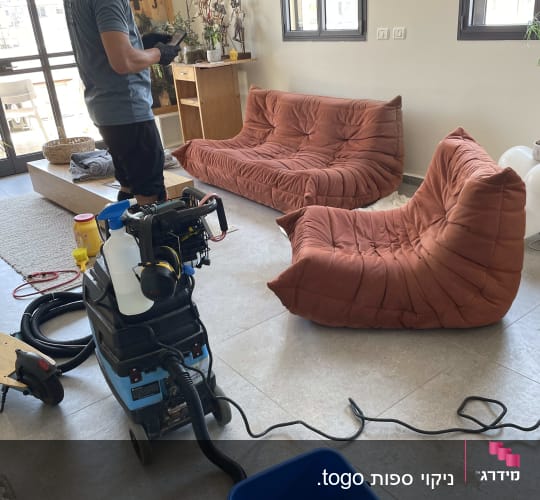 אדם מנקה ספות עם מכונת ניקוי ושואב אבק